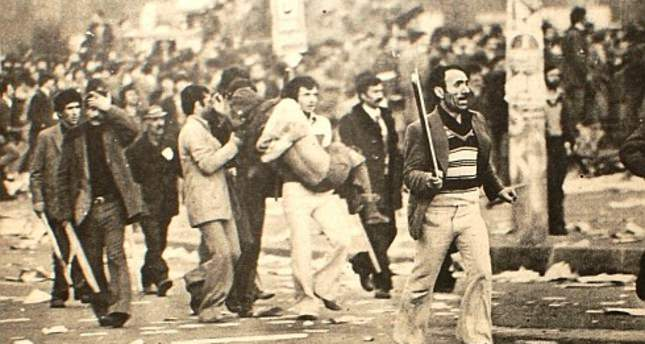 Click and drag to move 1. Mai Demonstration auf dem Taksim-Platz in İstanbul, 1977. Zum Selbstschutz mit Holzschlägern bewaffnete Gewerkschaftsdemonstrant*innen tragen Verletzte und fliehen vor dem Beschuss von den Dächern umliegender Gebäude und vor den gepanzerten Fahrzeugen der Polizei.